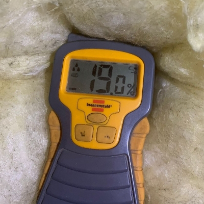 moisture meter against old floor insulation showing a value of 19% moisture